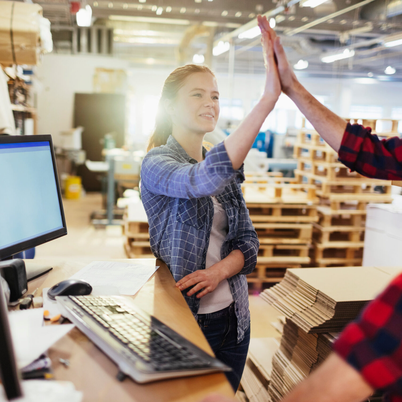 Two Caucasian coworkers congratulating each other while working in a warehouse